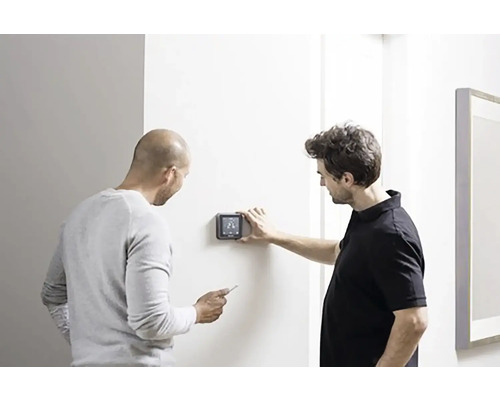 Dva muži instalují digitální termostat na zeď