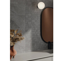 Koupelna s šedými obklady stěn v kamenném vzhledu, zrcadlem a lampou