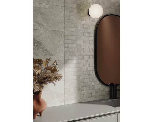 Nástěnná dekorace s obklady s kamenným vzhledem a mozaikovými obklady, kombinovaná se zrcadlem a lampou