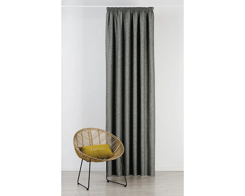 Látkový závěs vedle ratanového křesla s polštářem