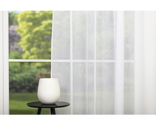 Okno s bílým závěsem a váza na příručním stolku