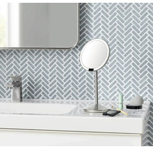 Na umyvadle stojí kulaté kosmetické zrcadlo s podstavcem