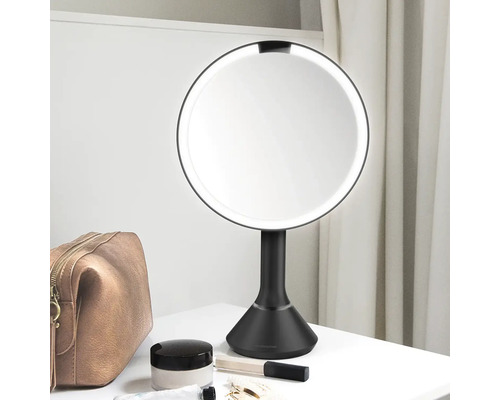 Osvětlené kosmetické zrcadlo na stole s kosmetickými produkty.