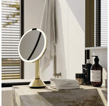 Osvětlené kosmetické zrcadlo v koupelně na mramorovém povrchu s ručníky a produkty péče o pleť.