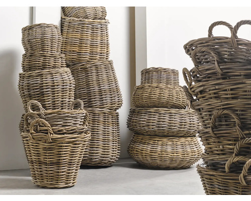 Několik naskládaných proutěných košů různých velikostí s držadly.
