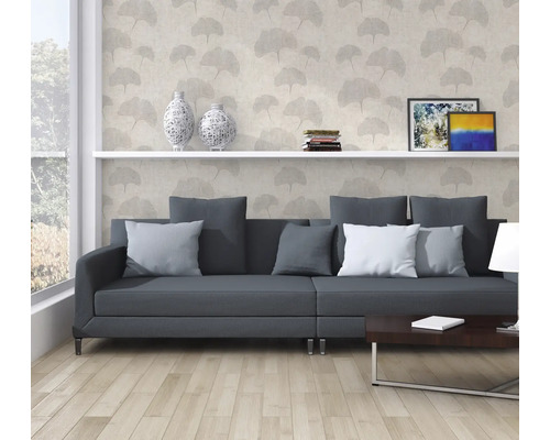 Obývací pokoj s šedou pohovkou, knihovnou a dekorativní tapetou s rostlinnými motivy.