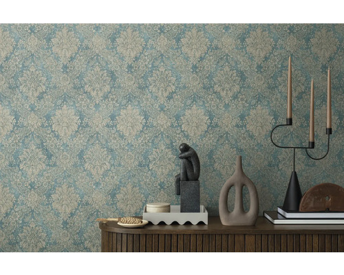 Dekorativní interiér se vzorovanou tapetou, skulpturou, svícnem a dekorativními prvky na dřevěné skříňce.