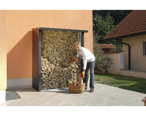 Osoba plní koš na dřevo u regálu na dřevo