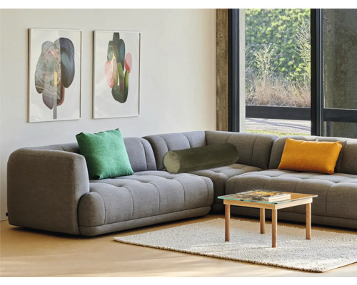 Obývací pokoj s šedou rohovou sedačkou, polštáři a malým stolem