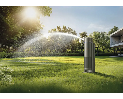 Zavlažovač trávníku zavlažuje zahradu před moderním domem.