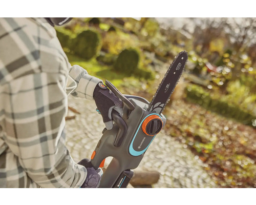 Osoba obsluhuje akumulátorovou řetězovou pilu Gardena na zahradě.