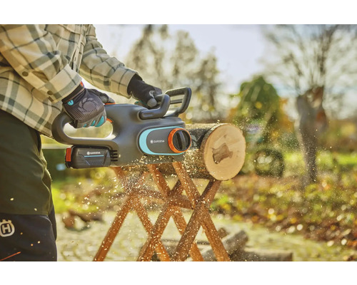 Akumulátorová řetězová pila v akci při řezání špalku na kozlíku