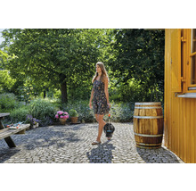 Žena nese ponorné tlakové čerpadlo v zahradě se stromy a květinami