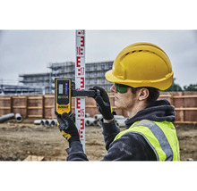 Stavební dělník s laserovým dálkoměrem DeWalt na nivelační lati