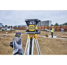 Rotační laser DeWalt na stativu se stavebním dělníkem v pozadí