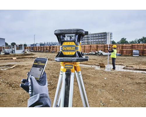 Rotační laser DeWalt na stativu se stavebním dělníkem v pozadí