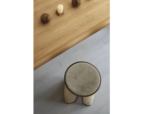 Pohled shora na kulatou stoličku s kožešinovým potahem a dřevěný stůl s dekorací