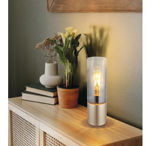 Dekorativní stolní lampa se skleněným válcem na dřevěném stole