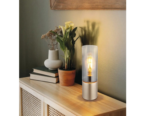 Dekorativní stolní lampa se skleněným válcem na dřevěném stole