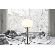 Dekorativní stolní lampa s kulovitým stínidlem vedle okna.
