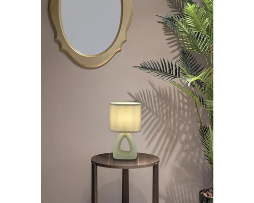 Dekorativní stolní lampa na odkládacím stolku vedle zrcadla a rostliny