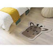 Pokojová scéna s postelí, sedákem a kobercem ve tvaru hlavy žirafy.