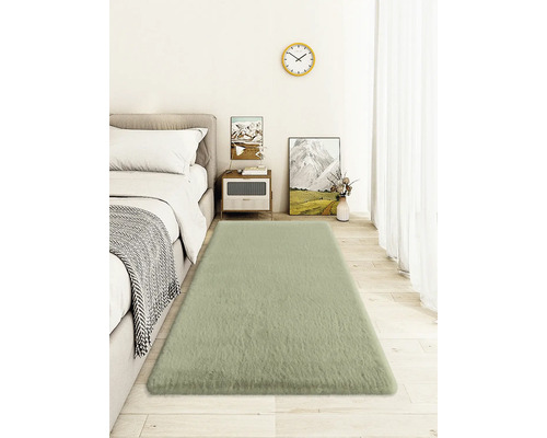 Ložnice s postelí, nočním stolkem, nástěnnými hodinami a obdélníkovým kobercem