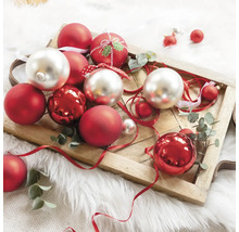 Ozdobné vánoční koule v červené a stříbrné barvě na dřevěném podnosu.