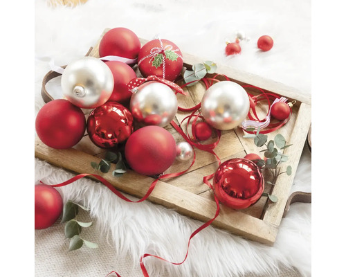 Ozdobné vánoční koule v červené a stříbrné barvě na dřevěném podnosu.