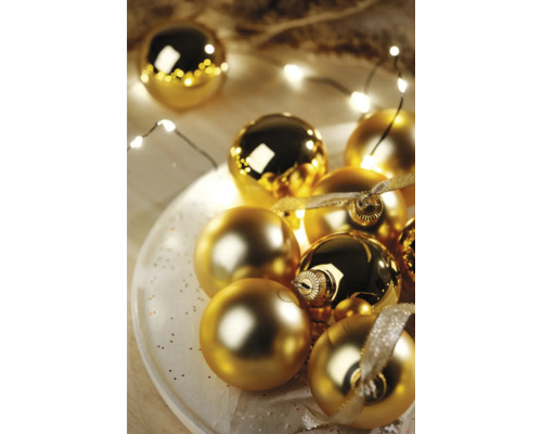 Dekorativní zlaté vánoční koule na talíři se světelným řetězem