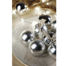 Dekorativní vánoční koule s lesklým povrchem a stuhami na talíři