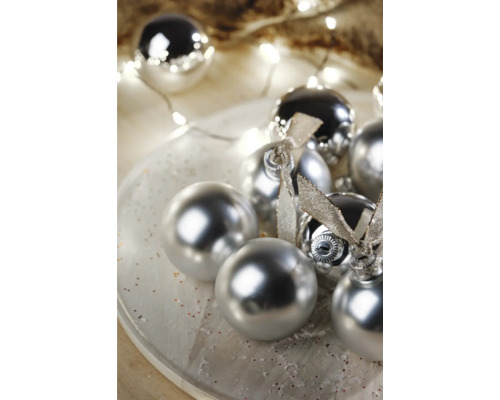 Dekorativní vánoční koule s lesklým povrchem a stuhami na talíři