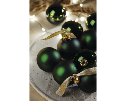 Dekorativní zelené vánoční koule na talíři se zlatými stuhami