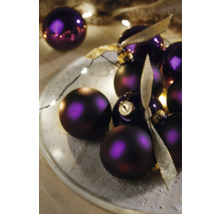 Dekorativní fialové vánoční koule s stuhami na talíři