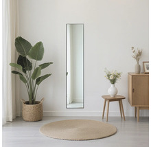 Pohled do místnosti s obdélníkovým zrcadlem, rostlinou a komodou