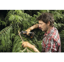 Muž stříhá větve stromu akumulátorovou prořezávací pilou.