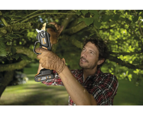 Muž stříhá větev akumulátorovými nůžkami na větve Worx Nitro.