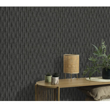 Detail stěny se strukturovanou tapetou, stolu s lampou a rostlinami