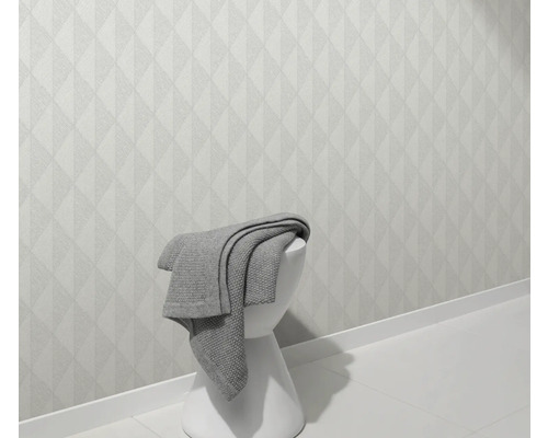 Světlá stěna s geometrickým vzorem a stolička s dekou