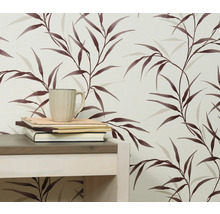 Detail stěny s tapetou s listovým vzorem, stolem, knihami a šálkem.