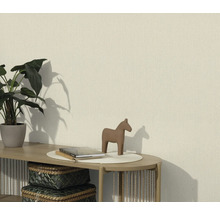 Obývací pokoj se strukturovanou tapetou, zdobený rostlinou, figurkou koně a knihami na stole