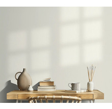 Světlá pracovna se stolem, hromadou knih, vázami a šálkem