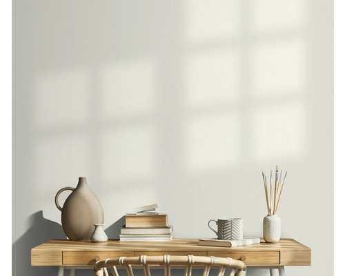 Světlá pracovna se stolem, hromadou knih, vázami a šálkem