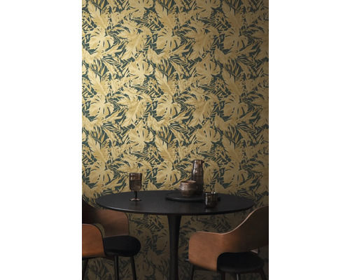 Pokoj s tapetou s motivem listů, jídelním stolem a židlemi.