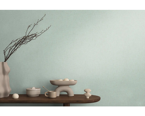 Dekorativní uspořádání na dřevěném stole před stěnou s textilní tapetou