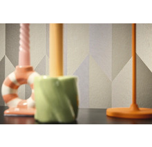 Detail vzorované tapety s geometrickými tvary v pozadí tří svícnů.