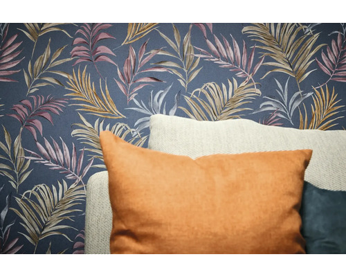 Dekorativní tapeta s designem listů a polštáře v popředí.