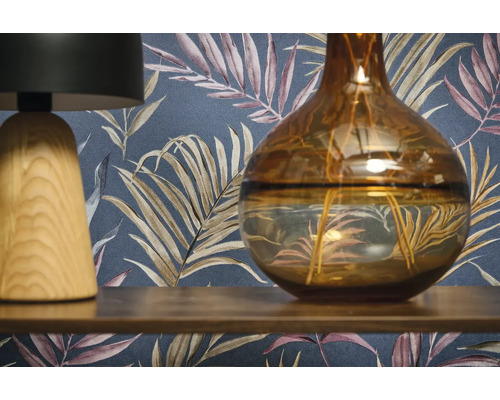 Dekorativní scéna s lampou, vázou a vzorovanou tapetou.