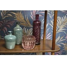 Dekorativní vázy a skleněné předměty na dřevěné polici před vzorovanou tapetou