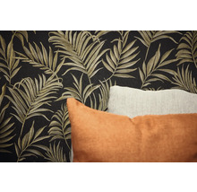 Detail stěny s tapetou s motivem listů a dekorativními polštáři